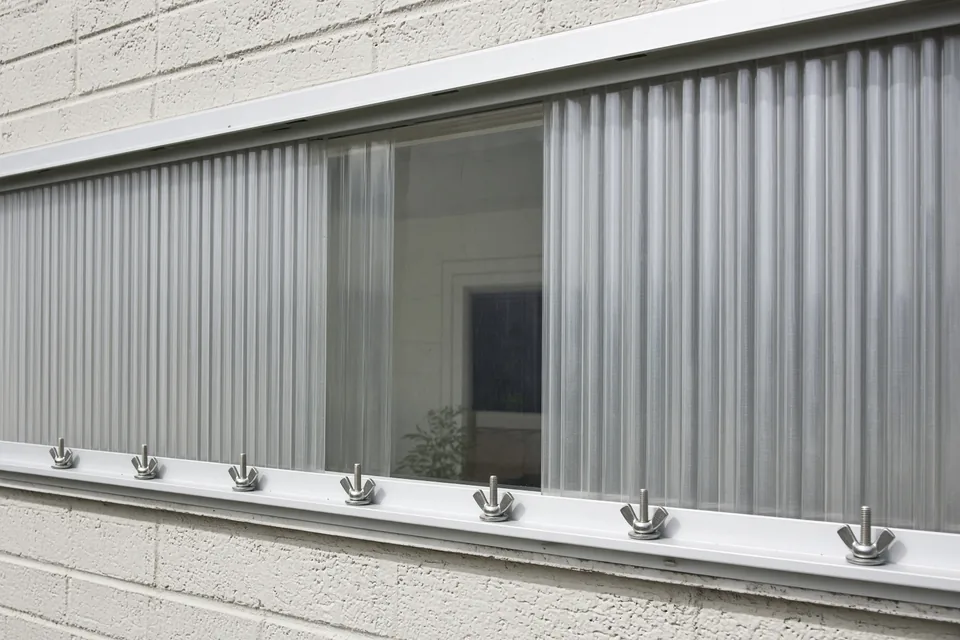 Corrugated aluminum storm panels with a clear polycarbonate center panel bolted into window tracks.