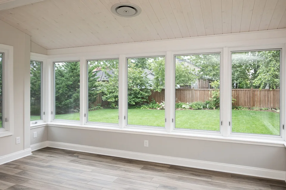 Interior of a four-season sunroom showing low-E double-pane windows, knee wall outlets, and sloped ceiling.
