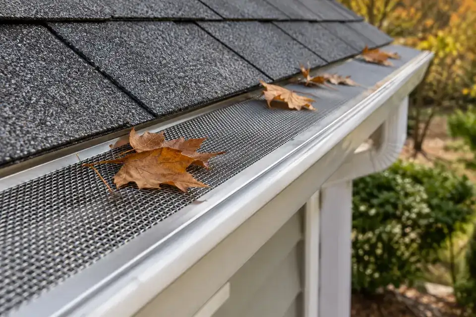 Fine stainless mesh gutter guard keeping leaves out of the trough along the roof edge.